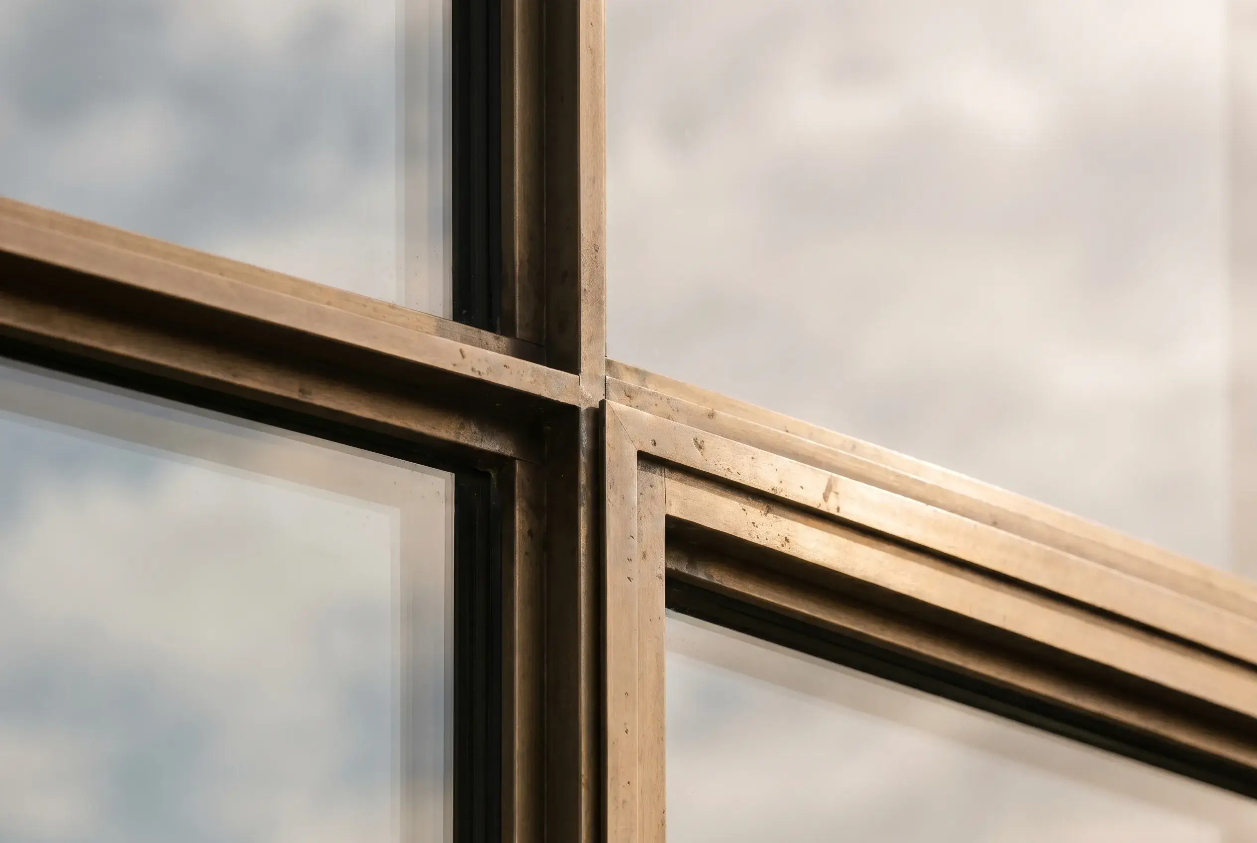A bronze cross junction in a window, sky beyond