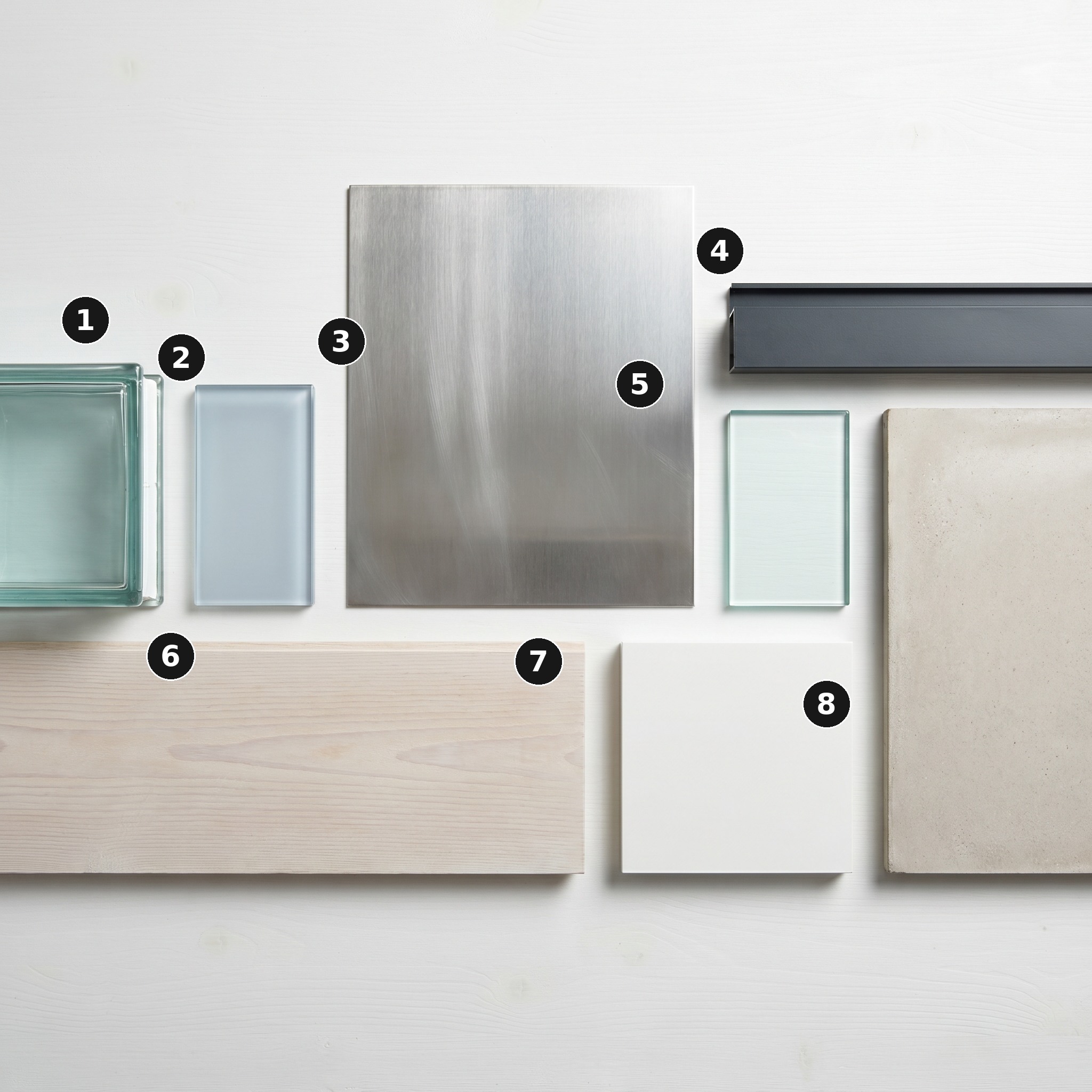 Overhead flat lay of 8 material samples from Island Home, Shoreditch — Architectural glass block, Switchable electrochromic smart glass, Brushed stainless steel, Anthracite-grey powder-coated aluminium frame, Frameless clear float glass, Bleached pale Douglas fir floor plank, White matt-lacquered MDF and Pale polished concrete — arranged on a soft warm-white painted timber surface.